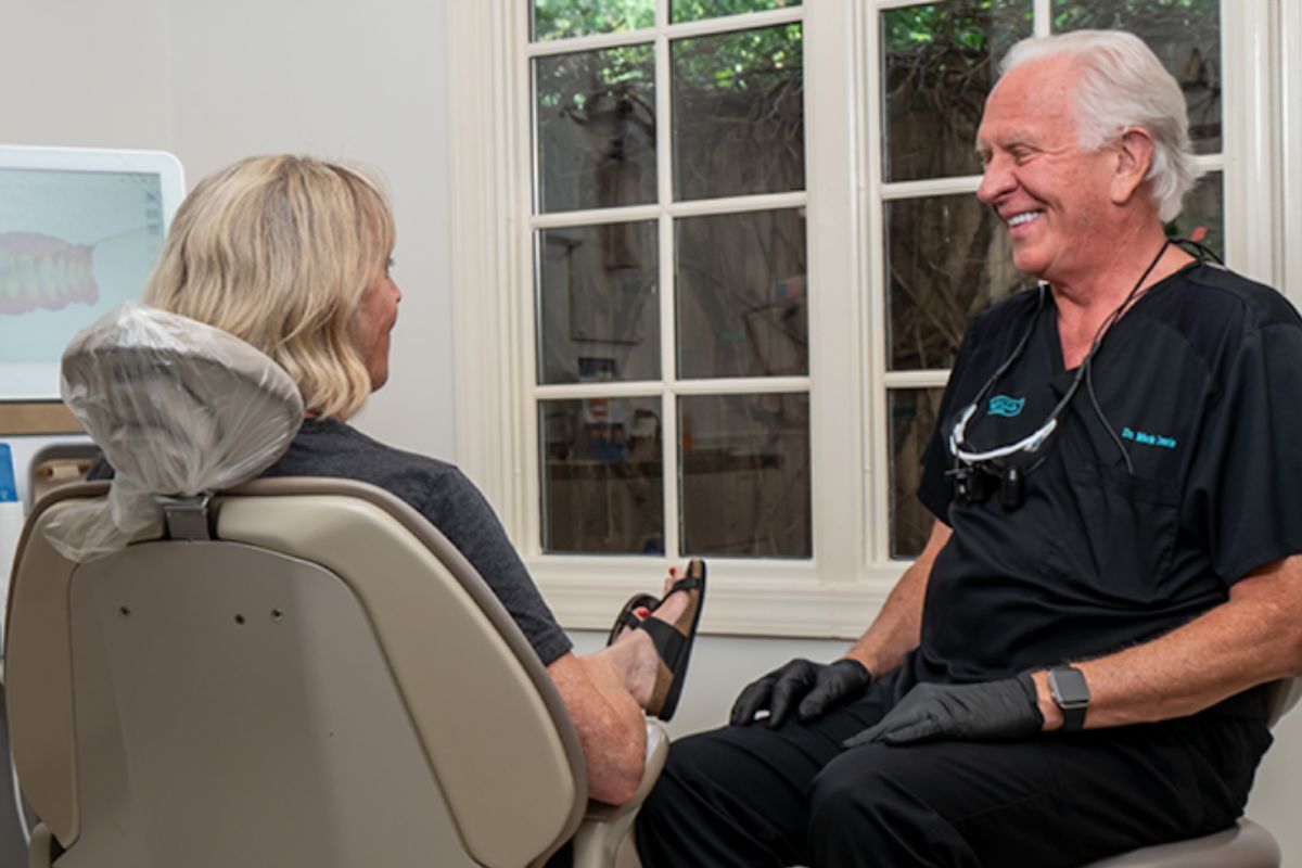 Dr. Mark Davis smiling while consulting with a patient in a comfortable dental treatment room in Tulsa.